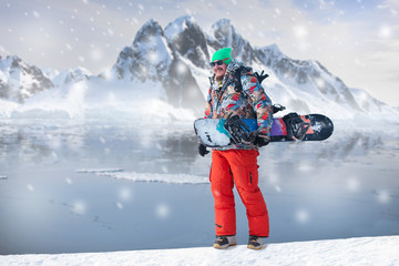 Male snowboarder against panoramic winter mountains background