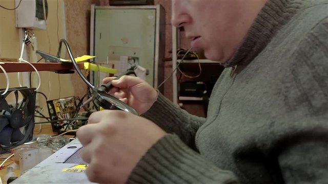 Engineer preparing new chip processor for installation on motherboard of smartphone iphone. White man in old workshop