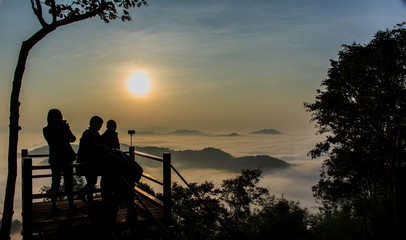 Silhouettes of tourists on viewpoint with the mountain in mornin