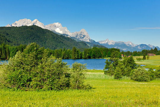 Sommerlandschaft in den bayerischen Alpen, hinten ein Bergsee und das Wettersteingebirge mit der Zugspitze