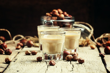 Creamy liqueur with hazelnuts, vintage wooden background, select