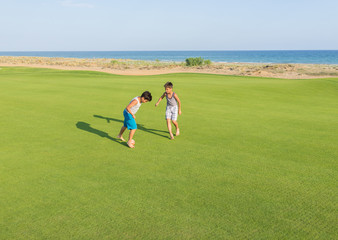 Fototapeta na wymiar Happy children on summer gulf grass terrain having fun and happy