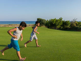 Happy children on summer gulf grass terrain having fun and happy