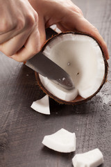 Opening up and carving a raw coconut with hands using a knife