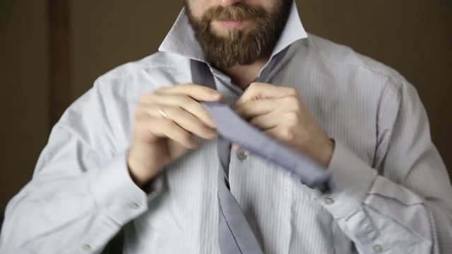 Businessman tying a tie on brown background