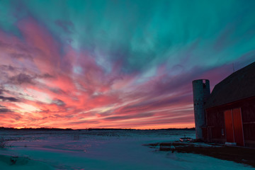Amazing sunset sky with northern lights over the red old barn in Michigan