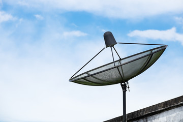 Satellite dish on roof with blue sky and some cloud.
