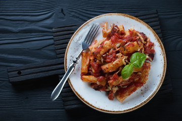 Glass plate with ziti, black wooden background, flat-lay view