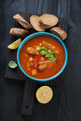 Black wooden serving board with tilapia chowder, high angle view