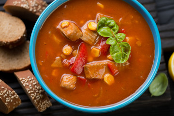 Close-up of tomato soup with tilapia fish in a blue ceramic bowl