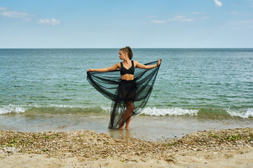young woman in a black chiffon dress on the seashore