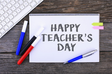 Notebook with HAPPY TEACHER'S DAY Handwritten on wooden background