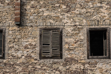 Fototapeta na wymiar Old building in Northern Italy broken down and worn with windows and old stone facade