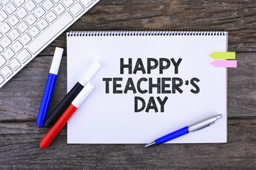Notebook with HAPPY TEACHER'S DAY Handwritten on wooden backgrouND