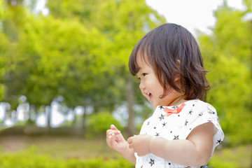 新緑バックに喜ぶ幼い女の子の横顔