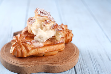 Tasty eclairs on wooden table