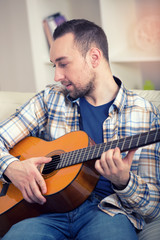 Obraz premium Portrait of a young man playing the guitar at home