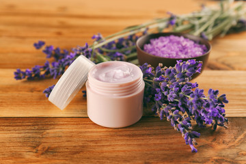 Nourishing cream and lavender flowers on wooden table, closeup
