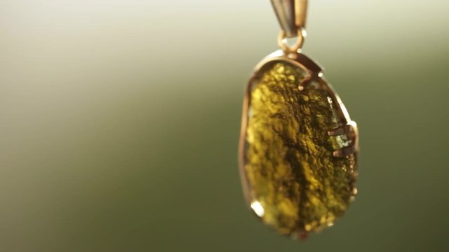 silver pendant with a stone vltavin on blurred background
