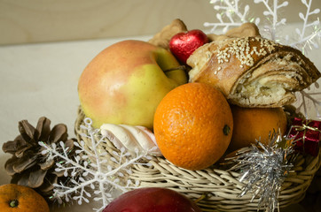 Straw basket with pastries,yellow apple, tangerines,pine cones and snowflakes

