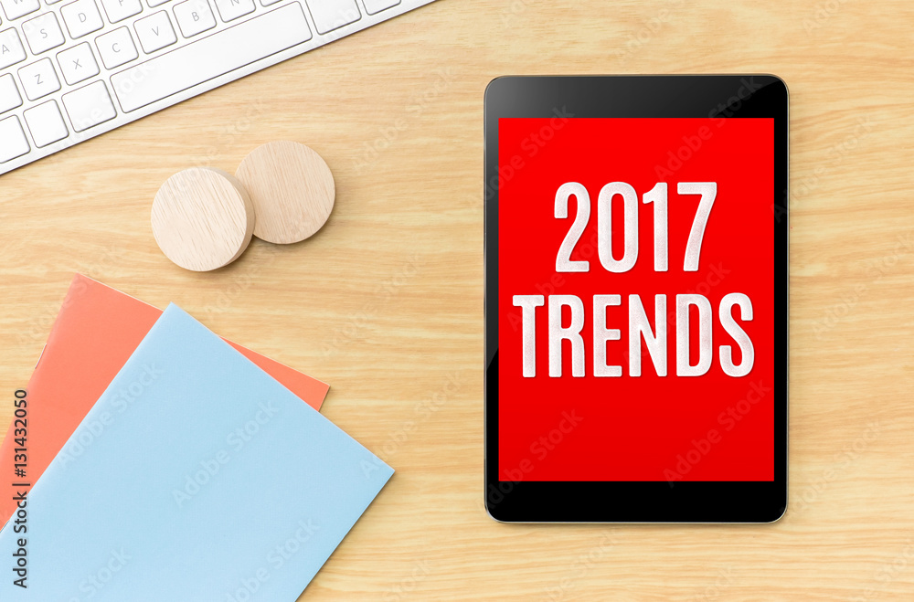 Poster top view of 2017 trends on screen tablet with blue notebook and
