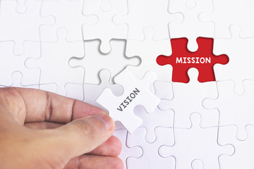 Business Concept - Female hand and missing puzzle with VISION and MISSION