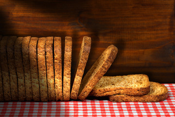 Healthy rusks of wholemeal flour on a table with checkered tablecloth and wooden wall