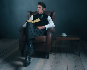 Retro victorian dickens style man reading book by candlelight.