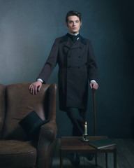 Retro dickens style man standing with cane next to leather chair