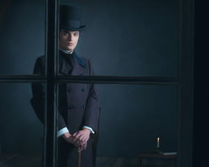 Dickens style man standing with cane behind window.