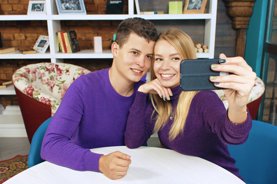 Young couple man and woman doing selfie. Home or a coffee shop