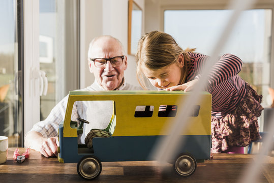 Grandfather and granddaughter assembling toy bus