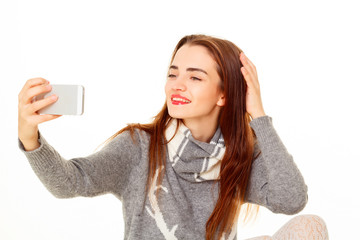 Happy young beautiful girl making selfie on the phone in sweater