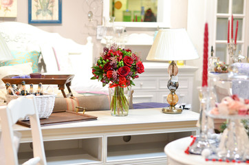 Букет из красных роз в стеклянной вазе на фоне красивого интерьера