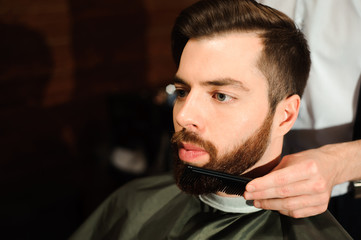 Master cuts hair and beard of men in the barbershop