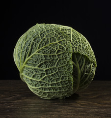 Ripe green savoy cabbage on a black background.