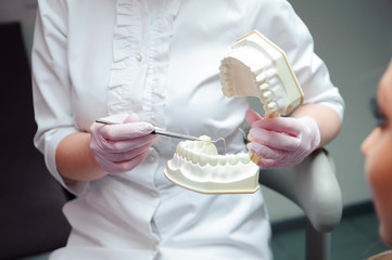 female dentist talking with female patient. Dentist holding a mo