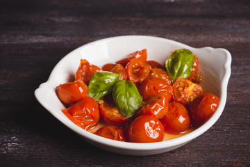 Tomatoes and basil leaves with olive oil on old wooden table. Shallow depth of field. Toned image.
