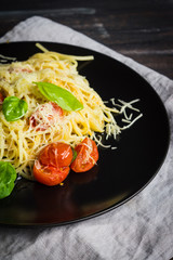 Pasta with tomatoes and basil on the dark background. Shallow depth of field.