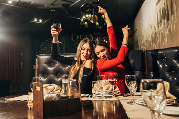 Two beautiful happy women having fun in a bar drinking wine