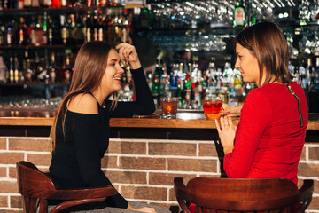 two women sitting at the bar,have fun smile