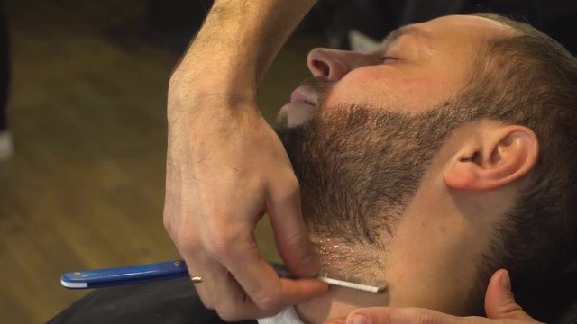 Barberman shaving beard of man