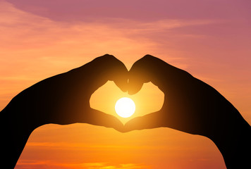 Naklejka premium sunset in the middle silhouette hands heart shape 