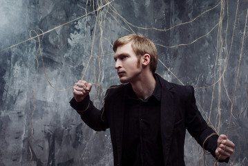 Young man tries to break the shackles. Concept of manipulation and slavery