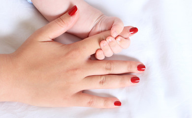 Baby hand gently holding adult's finger