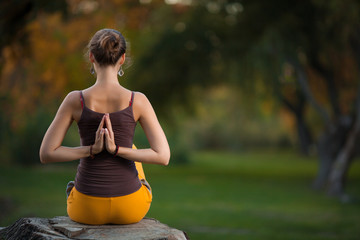 Young woman doing yoga exercises in the autumn city park.