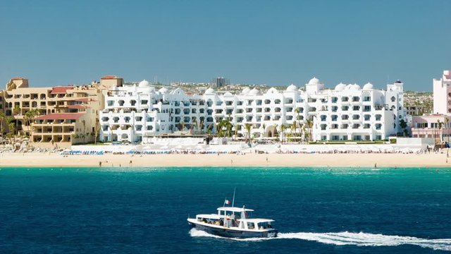 Luxury Mexican Beachfront Resorts in Cabo San Lucas Wide Shots with Passing Boat and Blue Sea Water on a Sunny Day
