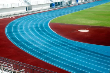 Fotobehang Stadion Blauwe atletiekbaan in stadion. lopende spoorlijn.