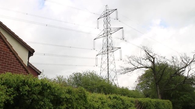 An electricity pylon towering over houses filmed with a jib