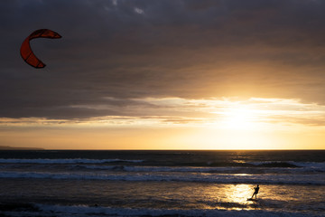 Silhouette of a kitesurfer riding at sunset with cloudy sky on the background, Kuta, Bali, Indonesia